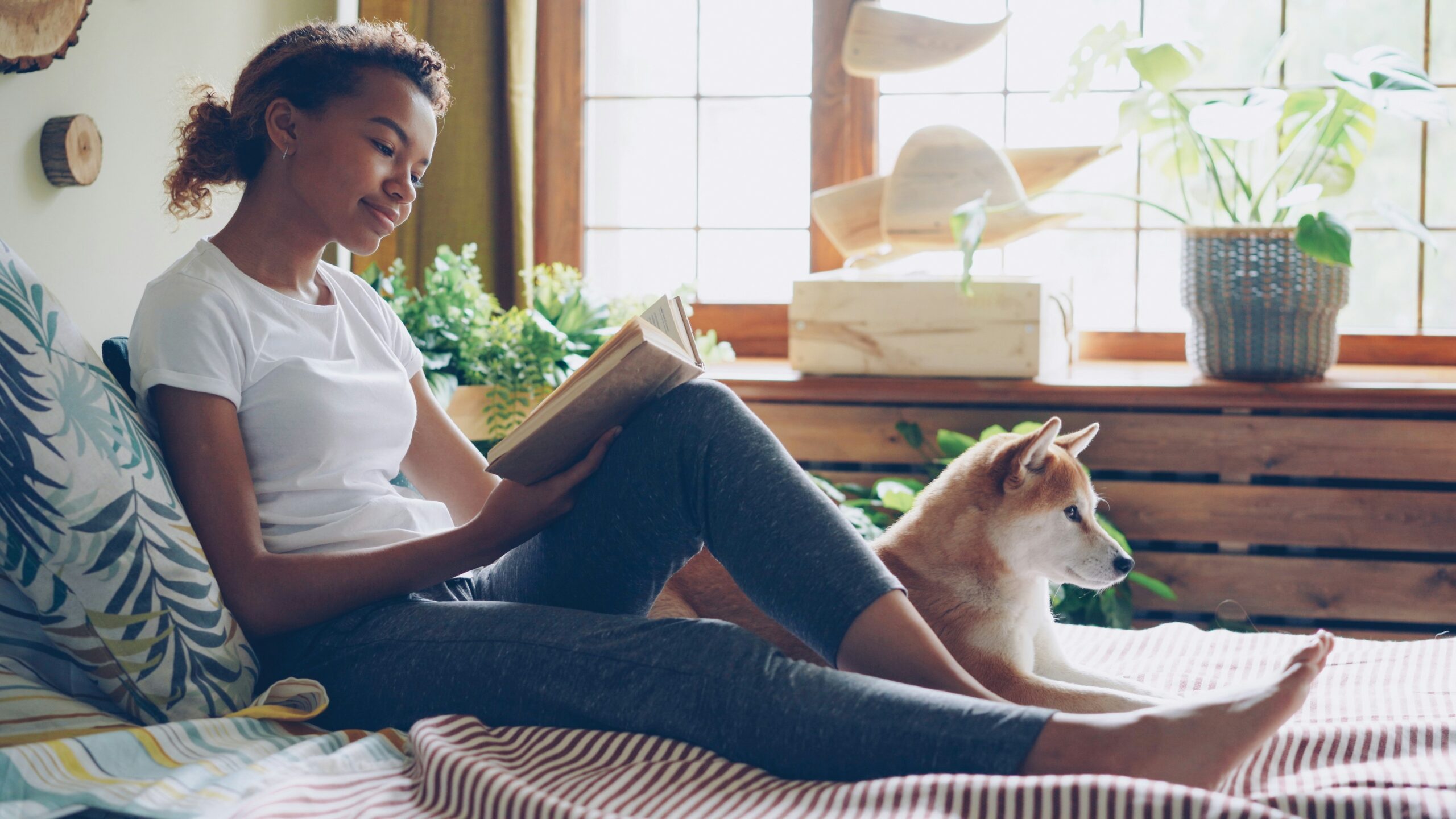 Mujer leyendo junto a su perro en casa, momento de calma y cuidado